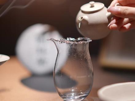 猫耳朵|生普太霸道?试试这杯温柔的例外~ 这个点,天将暗未暗,是一天里我最喜欢的蓝调时刻。
黑桌子用了很久了,很沉稳,能把白色器物衬得很安静,也能把人从白天的嘈杂里,慢慢拉回来。
今天喝的是古树盟·望月家族中的一饼小甜心,2025年头春的高杆生普,它是「猫耳朵」特殊的小叶种茶。
🐱猫耳朵——它太会长了,鲜叶时一片片小叶子圆滚滚、毛茸茸的,像小猫支棱起来的耳朵。超级可爱!但是它非常稀少,制作难度也很高。
🪡撬茶的时候要轻一点,它很娇嫩,条索紧结,茸毛特别多。凑近闻干茶,有一点点花果香,不是那种扑面而来的浓烈,是藏在里面、躲猫猫等你慢慢发现。
🫖泡茶 今天用的空泥的小丸子侧把壶,白段泥的,90cc,小小的,握在手里刚好一掌心。热水浇下去的时候,泥料的颜色会变得更温润,像奥利奥白巧克力!
第一泡出得快。汤色透亮,细细的茶毫浮在光里,像山间清晨的薄雾。
🪷分到莲花杯里,杯子也是白段泥的,像个含苞待放的花骨朵。 第一口下去,第一反应是:这真的是生普吗? 不涩,不冲,没有新茶常有的那种“我很厉害你小心点”的攻击性。它很软,很甜,滑进喉咙的时候几乎没有感觉,喝完才慢慢回过味来——花香、果香、在嘴巴里绕来绕去。
有人问我“猫耳朵”初尝到底是什么味。 我想了很久,觉得最像的是:小时候夏天傍晚,和朋友们玩闹,大汗淋漓回到家,喝到第一口凉白开的甜。不是糖的甜,是那个瞬间,水本身变甜了。
🌄蓝调时刻,第二泡的时候,窗外彻底蓝了。 这种蓝很奇妙,让所有东西都安静下来。茶汤的颜色也变了,更深一点,更暖一点。茶汤也慢慢透出了果香,像无花果 熟浆果的甜润。
其实新手朋友们喝生普,大多怕翻车。 但猫耳朵真的不怕,90度也好,沸水也好,前半段快出汤,它都给得出温柔的那一面。
愿这一杯甜,能打开生普的大门
晚安。🌙
#氛围感茶生活 #一杯茶的仪式感 #生普入门 #猫耳朵生普 #茶生活美学