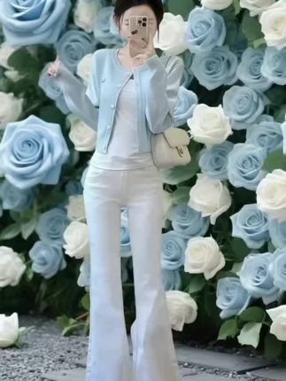 冰蓝针织开衫温柔轻搭,精致纽扣如星子散落;内搭纯白打底简约衬肤,微喇长裤垂坠显高,行走间漾起随性优雅。整体色调与蓝白玫瑰花海呼应,是春日里清新脱俗的穿搭范本,无论是打卡花墙还是日常通勤,都能轻松拿捏温柔氛围感。
