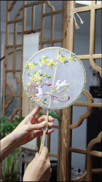 手把手教你制作一把非遗团扇 材料准备
- 圆形扇框(竹制或木制,直径可选20-30cm)
- 刺绣纱面(真丝或仿真丝材质,选半透质感更出效果)
- 剪刀、UHU胶水、热熔胶
- 小夹子
- 宋锦边(匣锦)
- 扇柄(木质扇柄,提前打孔便于后期组装)
- 流苏、装饰珠子(可选,用于扇柄装饰)
步骤详解
1. 挑选制作好的绣片
2. 封扇面
- 将绣好的纱面平整地绷在圆形扇框上,用小夹子固定边缘,确保纱面紧绷无褶皱。
- 把扇柄与扇框连接,可借助胶水固定。
3. 安装扇柄
4. 封扇底
5. 贴宋锦边条
6. 装饰收尾
- 在扇柄处穿上流苏、装饰珠子提升整体精致度。
小贴士
- 纱面较轻薄,操作时注意力度,避免扯坏纱面。
快动手做一把属于自己的中秋主题团扇吧,无论是自用搭配汉服,还是作为非遗手作礼物,都超有意义~
#龙姐姐的雅集 #在中秋向月亮许愿 #百young非遗计划 #这是我的非遗献礼 #中秋月满人团圆
