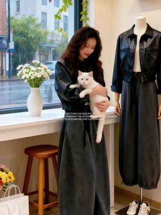 《雨巷衣店的猫与时光》   雨天,林薇的“素年”服装店被雨水冲刷得格外清新。她抱着白猫阿糯,望着窗外的雨丝,黑色皮衣与灰调阔腿裤衬得她随性又雅致。   店里的陈设温暖如春,紫藤花垂落窗边,花束与绿植点缀其间。她有时靠着吧台看平板,有时窝在沙发翻时尚杂志,阿糯总在脚边慵懒陪伴。   往来的客人常被这份宁静吸引,那件黑色短皮衣是她的得意之作,硬朗皮质与柔垂裤装碰撞出独特风格,像她的店一样,在喧嚣都市的雨巷里,守着一方关于服饰与生活的温柔角落,等风也等懂它的人。#韩系穿搭#气质穿搭#高级感穿搭#约穿搭#秋冬穿搭